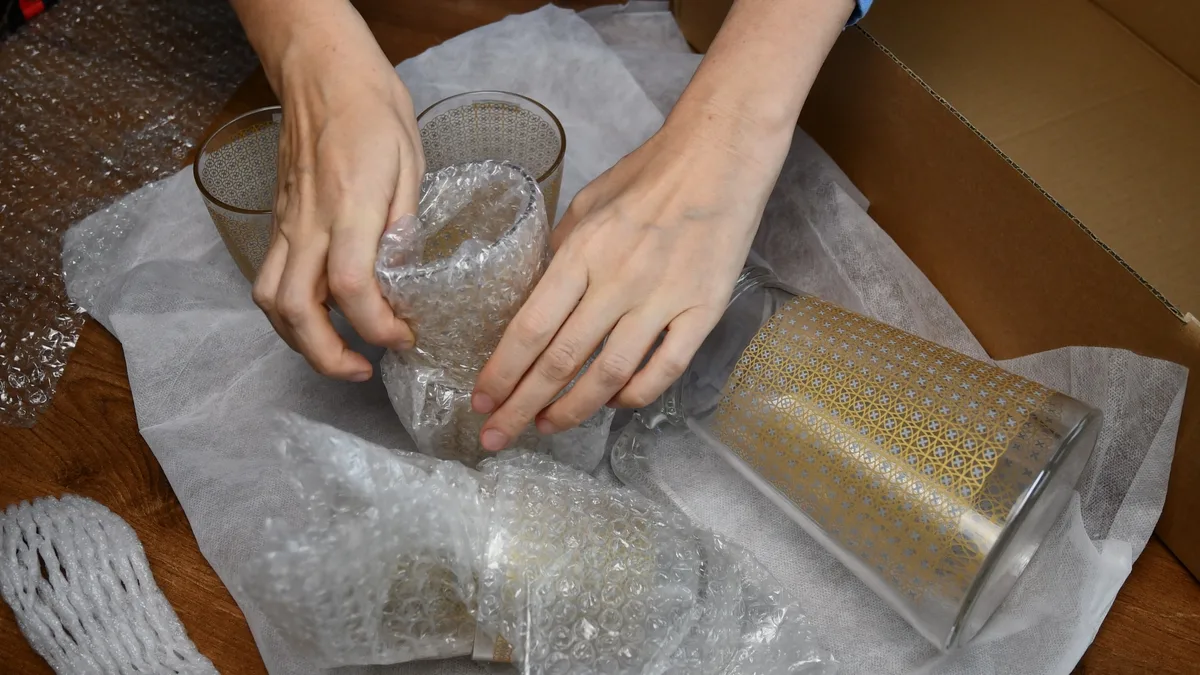 Glass pakket inn i bobleplast, klart til å legges i flytteesken