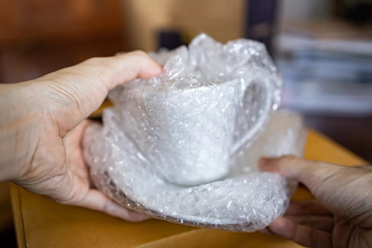 Kopp pakket inn i bobleplast før den legges i flytteesken
