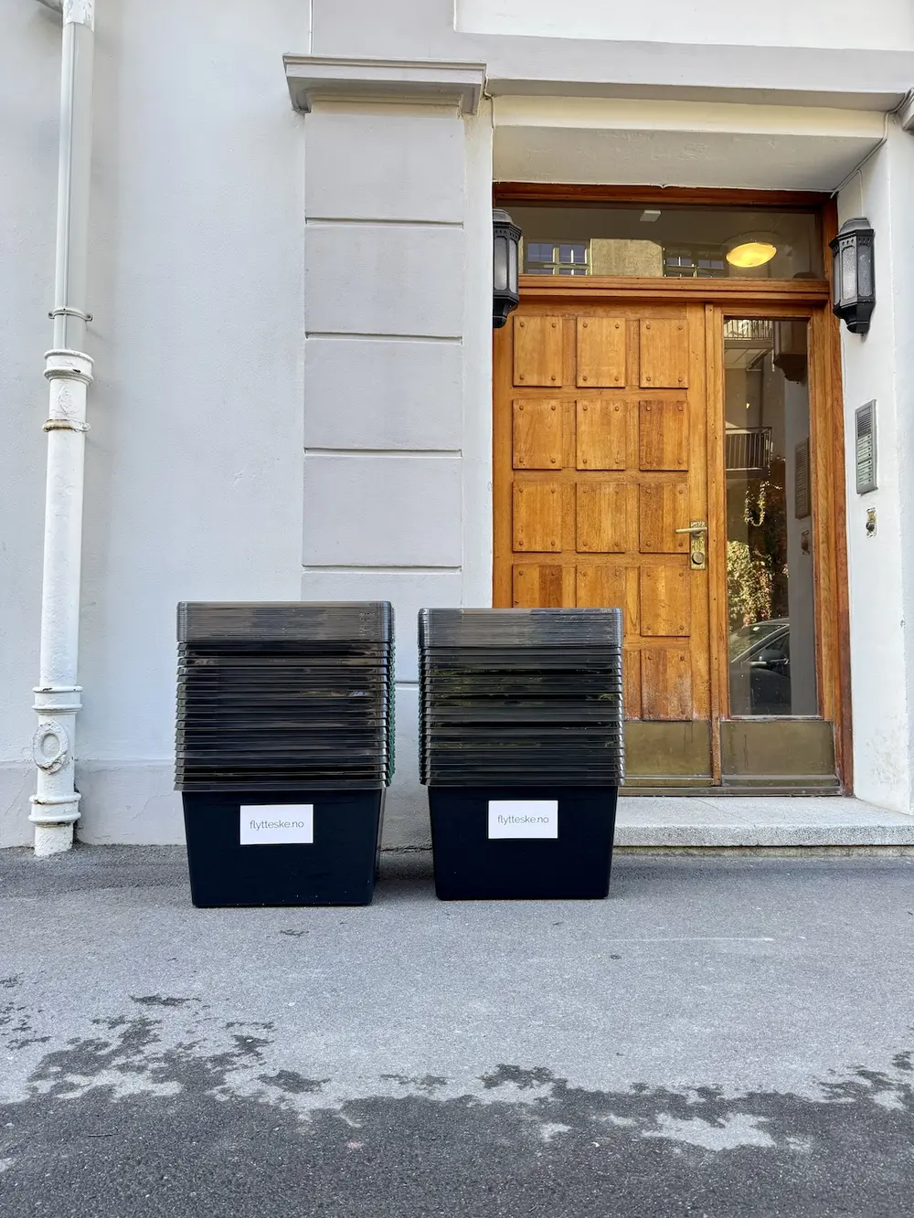 To rader med stablede, tomme Flytteske-kasser på fortauet utenfor en bygård i Oslo